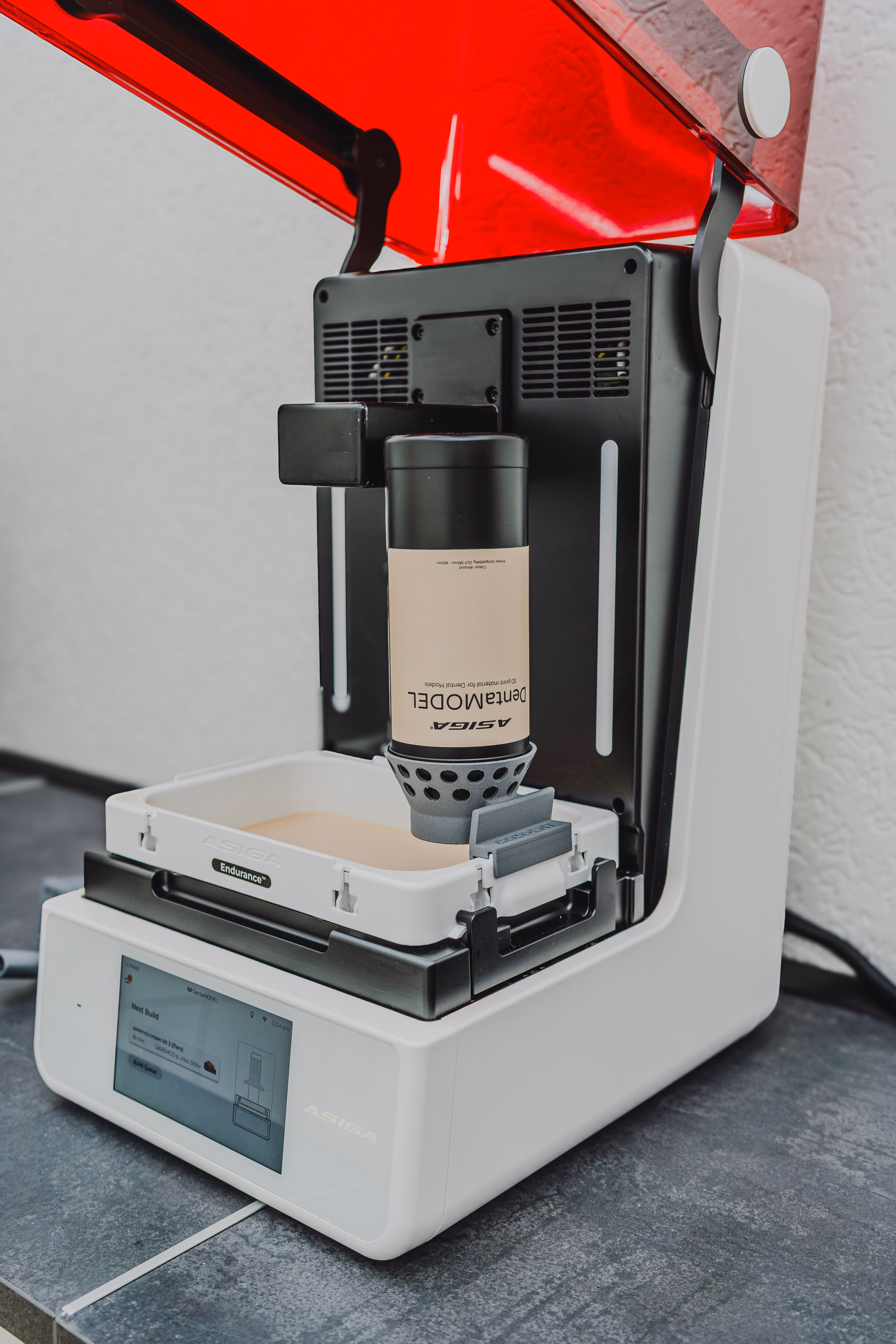 ASIGA 3D printer with red cover open, showing resin tank and upside-down resin bottle labeled Dental MODEL.