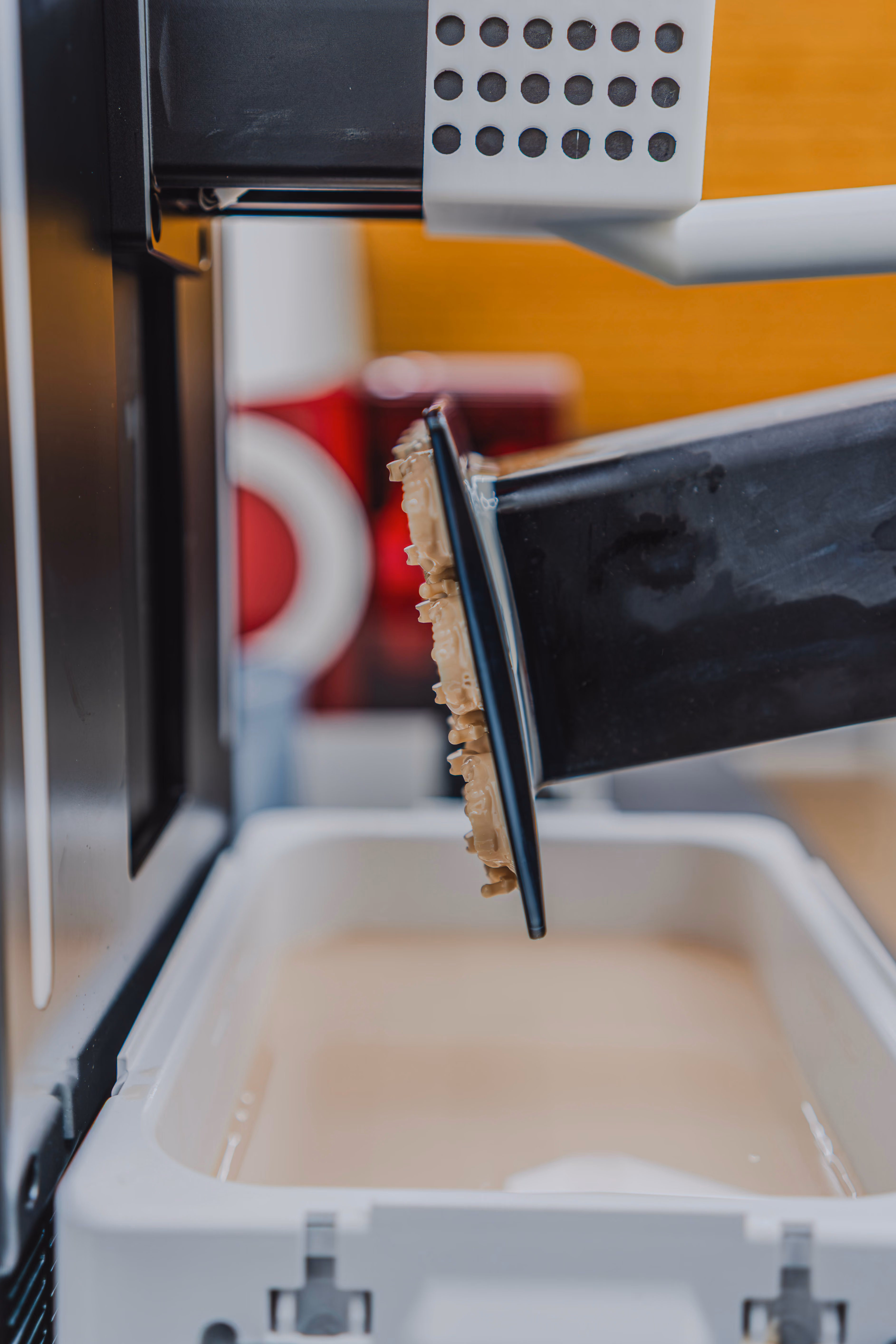 Close-up of a 3D printer platform holding beige printed parts inside the machine.