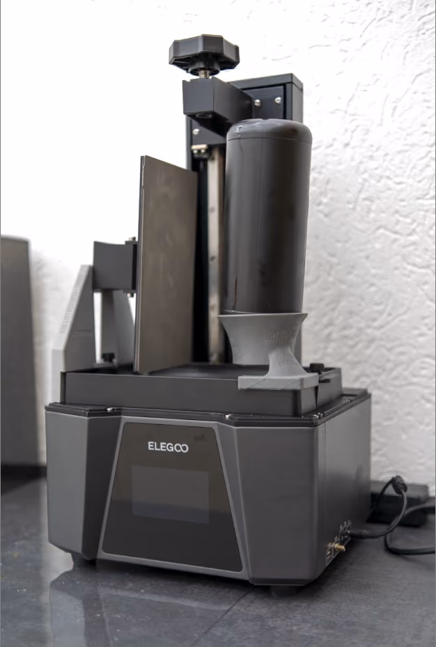 Elegoo device with a vertical cylindrical component and control knob on a dark surface.