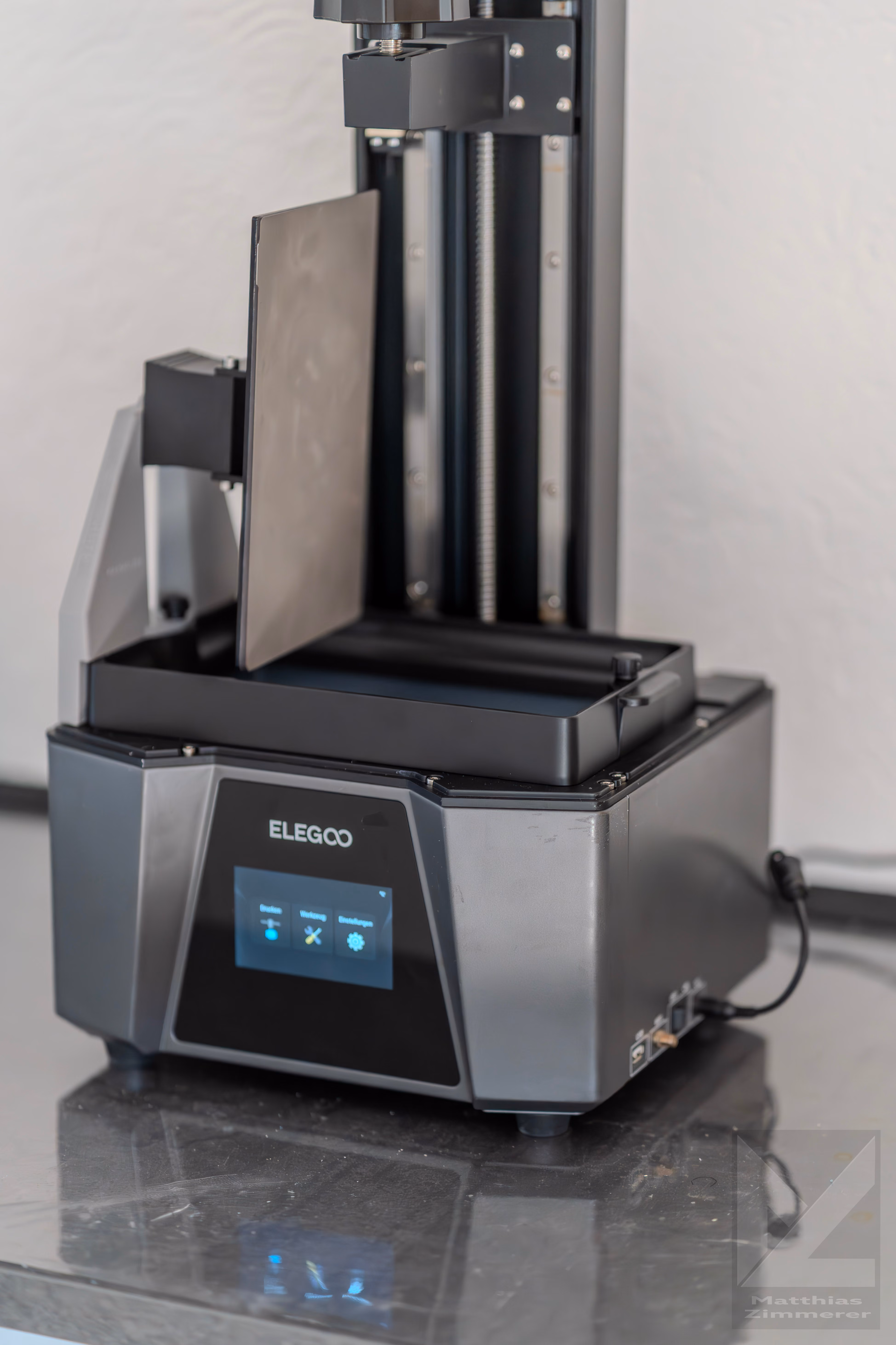 Elegoo 3D resin printer with touchscreen and vertical build platform on a reflective surface.