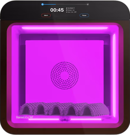 Formlabs Form Cure device curing a 3D printed object under purple light with timer and controls on top panel.