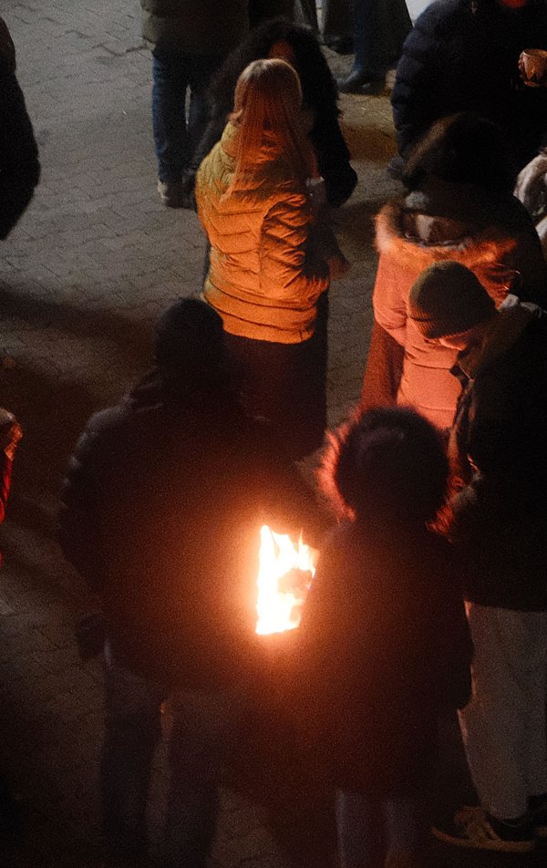 Gäste stehen am Abend im Hof um die Feuerschale