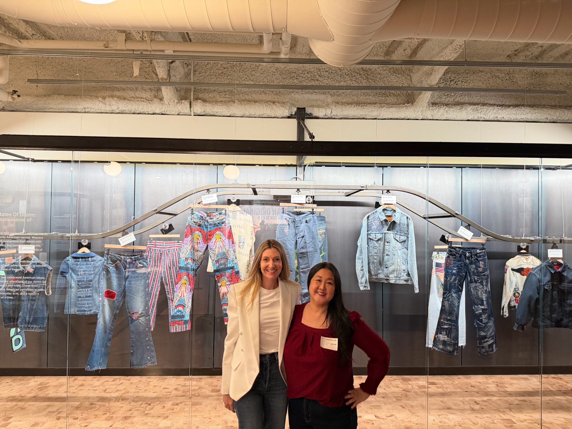 Two people in front of a denim clothing exhibit