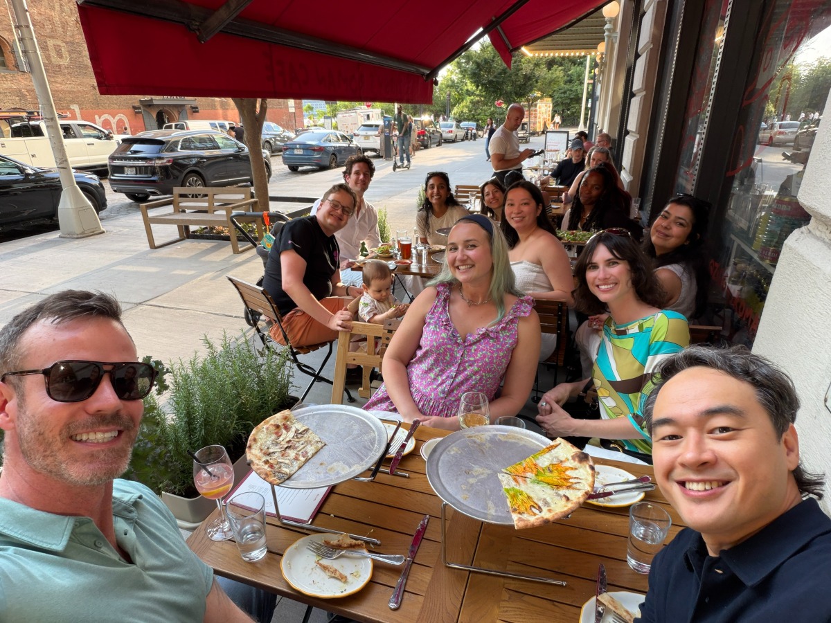 Raspberry AI team sharing a meal at a long outdoor table on a sunny hillside