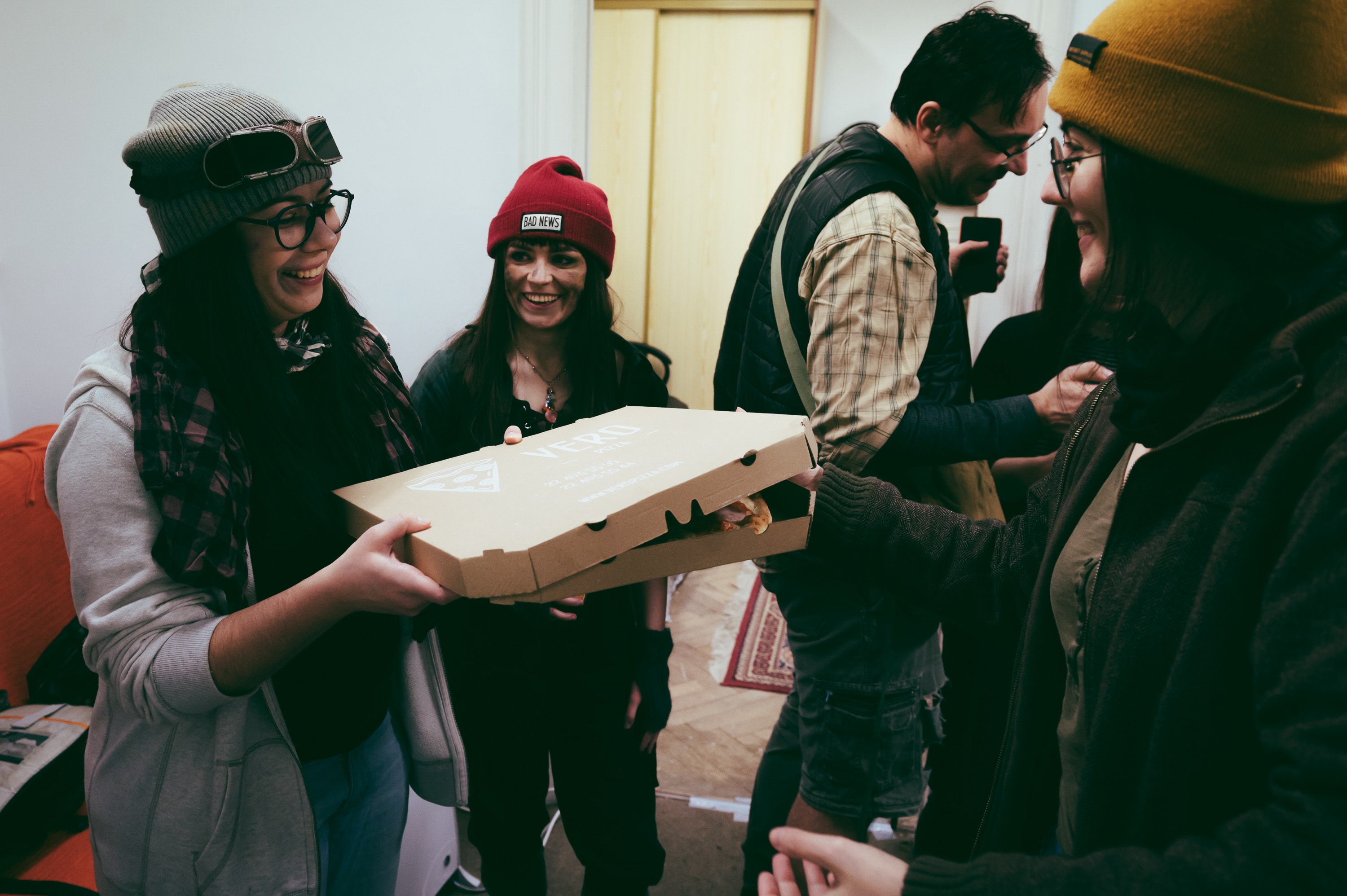 Game night guests smiling with a pizza box