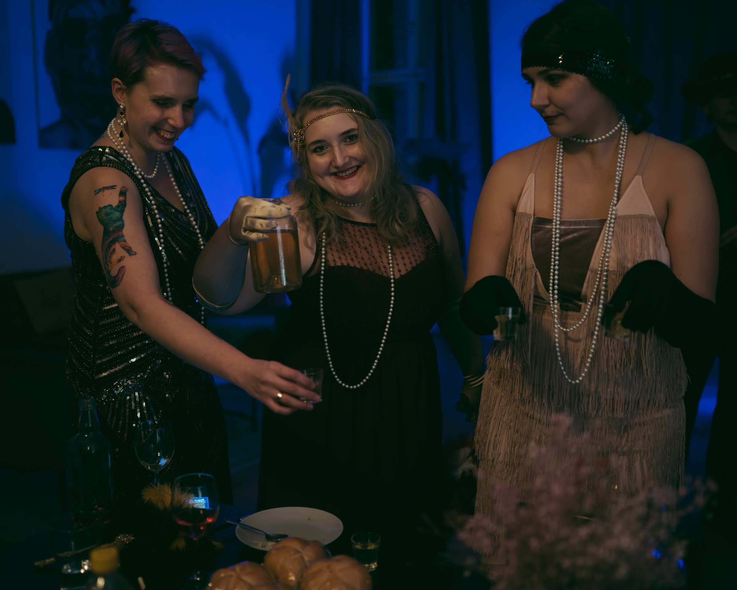 Guests in 1920s costumes enjoy a Halloween murder mystery party