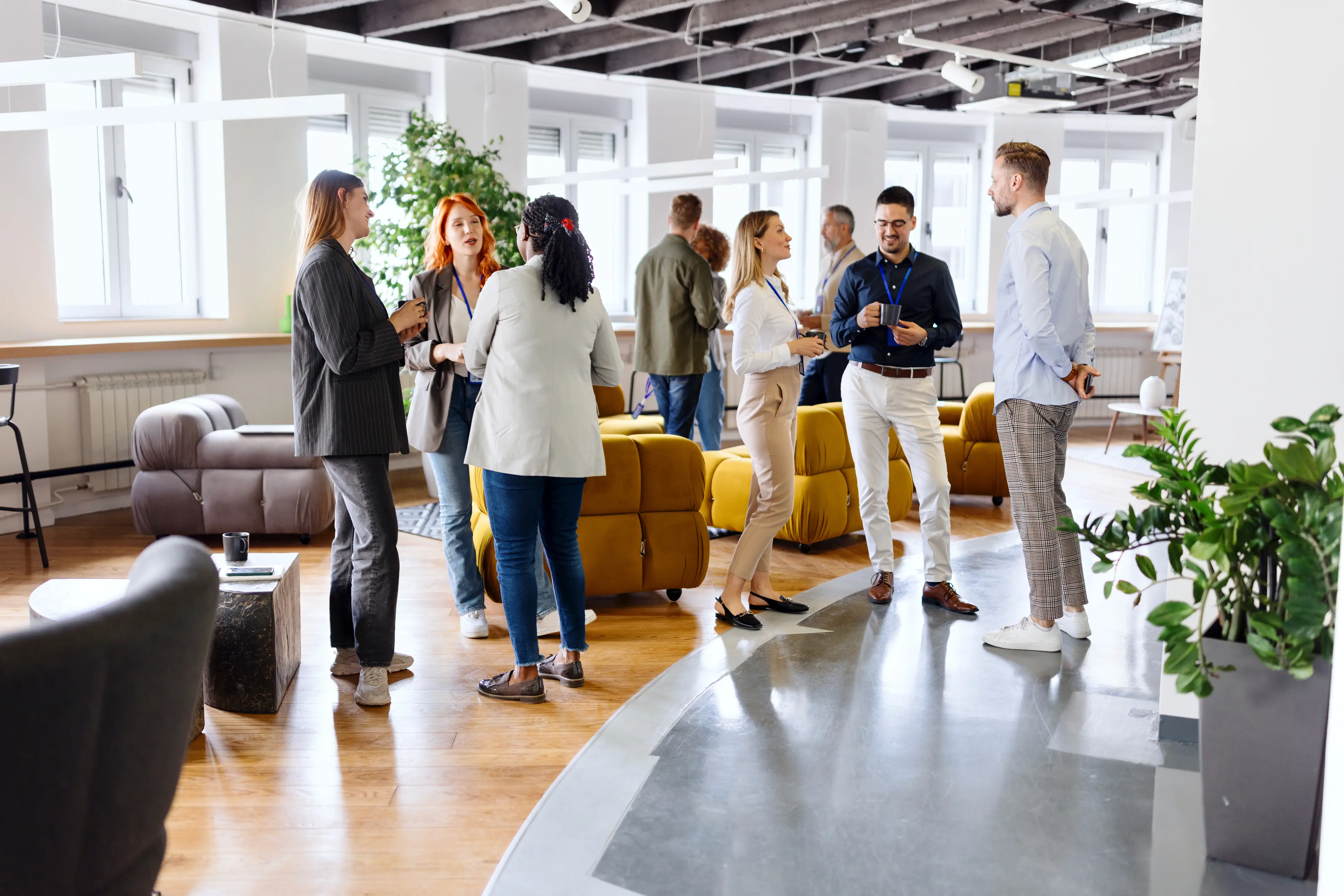A group of people standing in a room with a yellow couch.