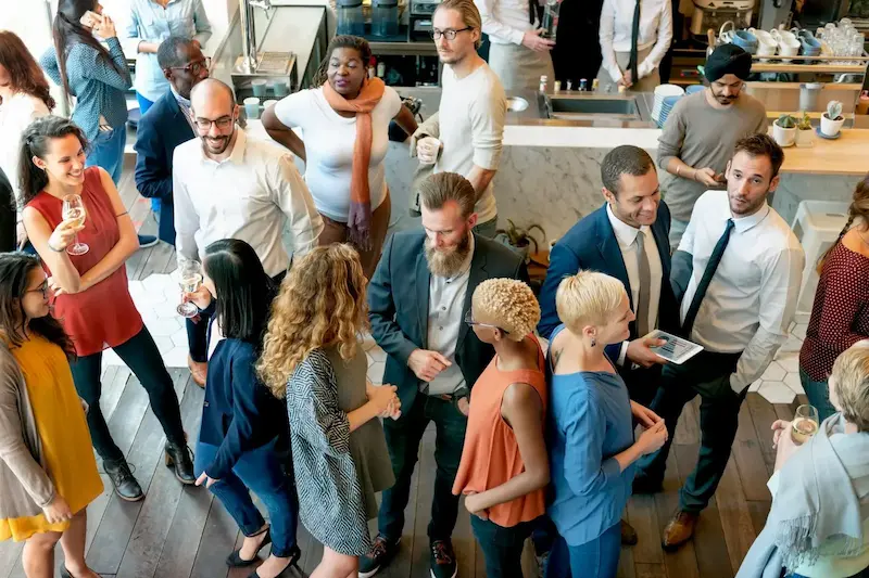 A diverse group of people socializing and networking in a modern indoor café setting.