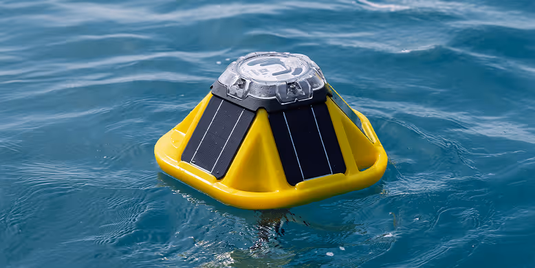 Yellow floating device with solar panels on water surface.
