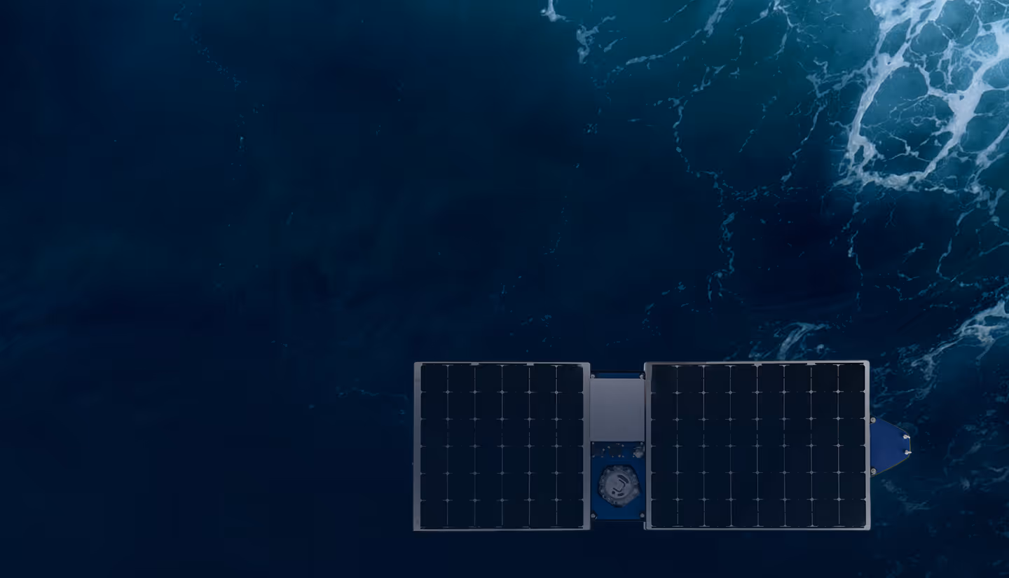 Aerial view of a solar-powered floating device on dark blue ocean water with waves.