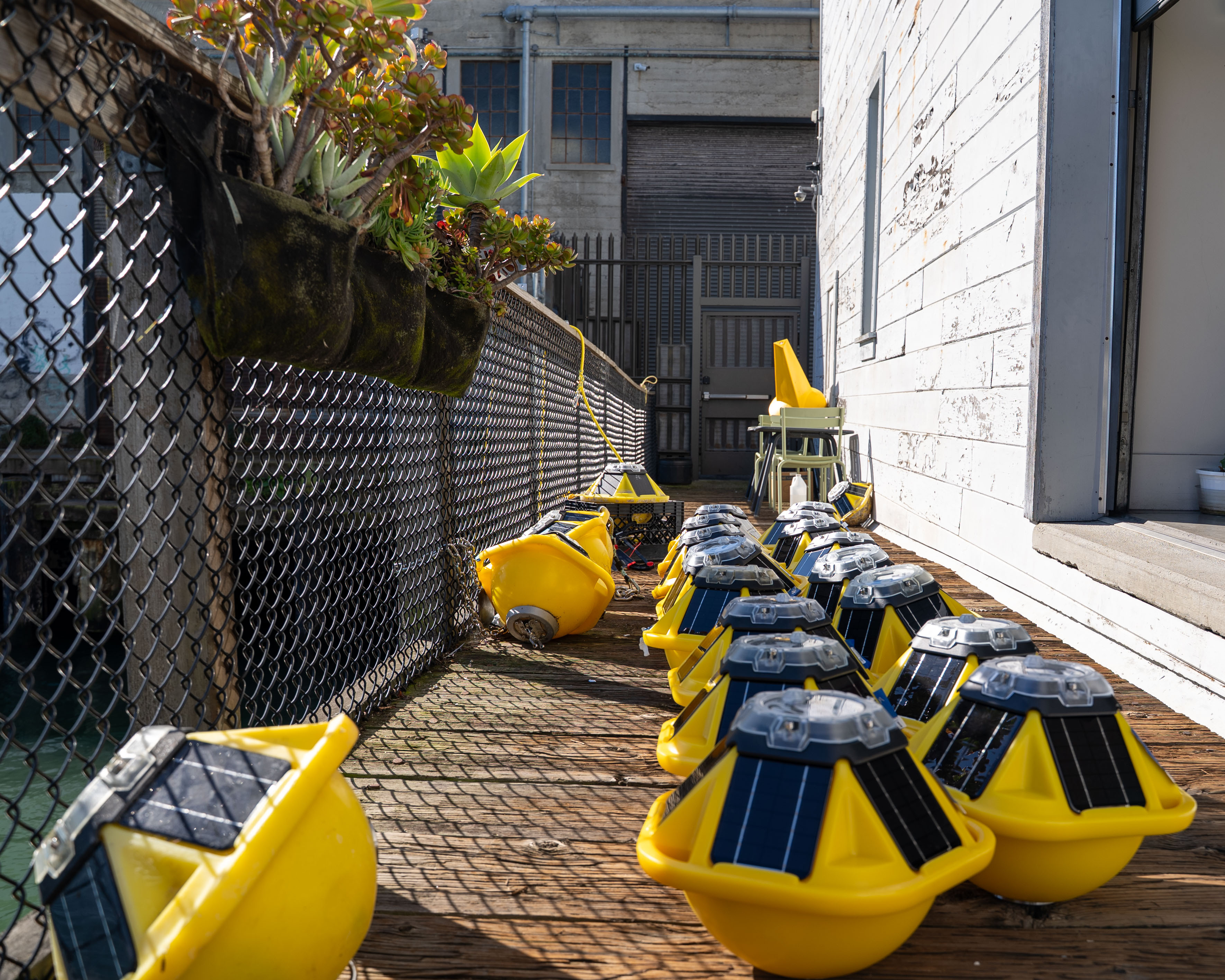 Multiple yellow Spotter ocean buoys with solar panels lined up on outdoor deck awaiting deployment