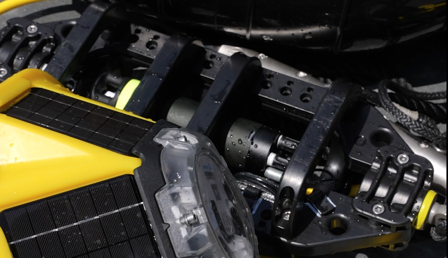 Close-up of a yellow solar-powered Spotter buoy alongside Spotter Sound hydrophone hardware in its mounting frame