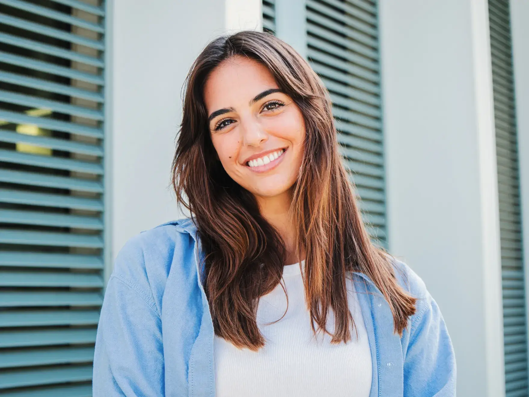 a woman standing in front of a window with shutters
