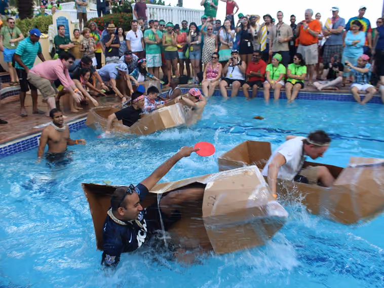 Teams racing cardboard boats in the Cardboard Boat Build