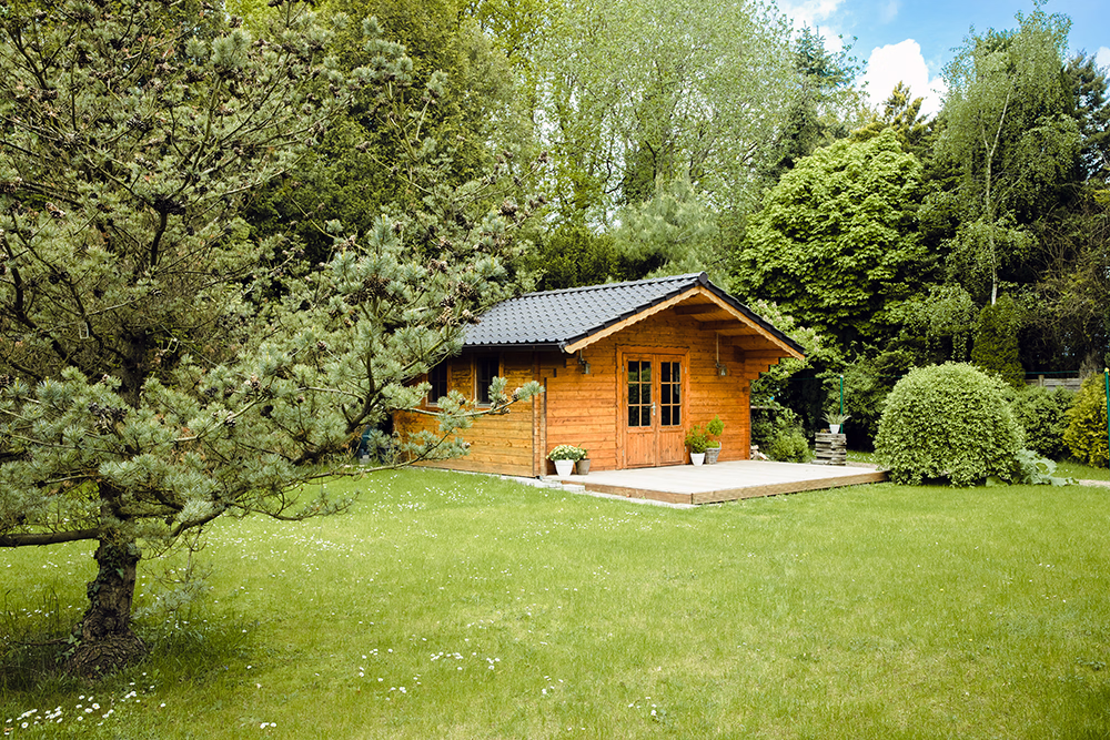 A garden with a wodden house in the background
