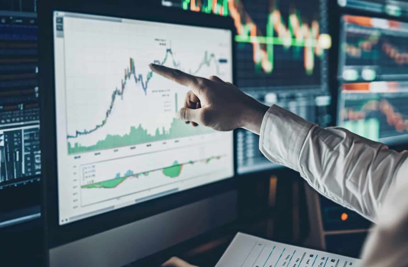 Doigt qui pointe une courbe financière sur un écran
