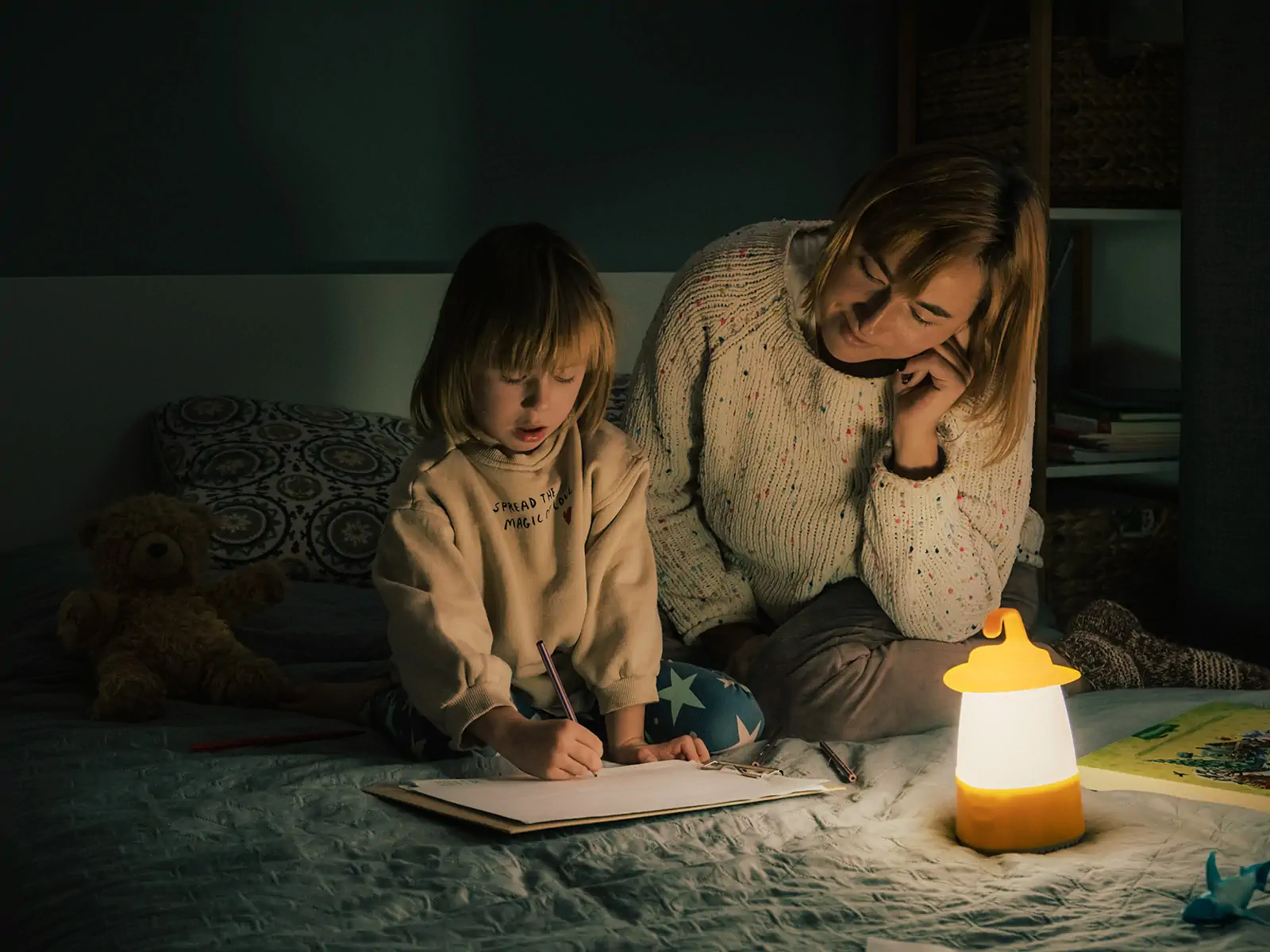 Mother and child coloring with a lantern during a power outage