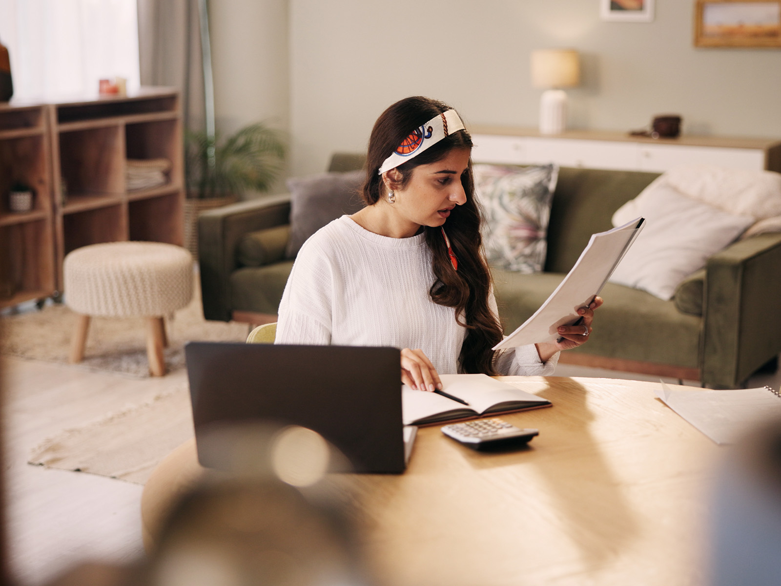 A woman holding a cup of coffee in one hand and her energy bill in the other.