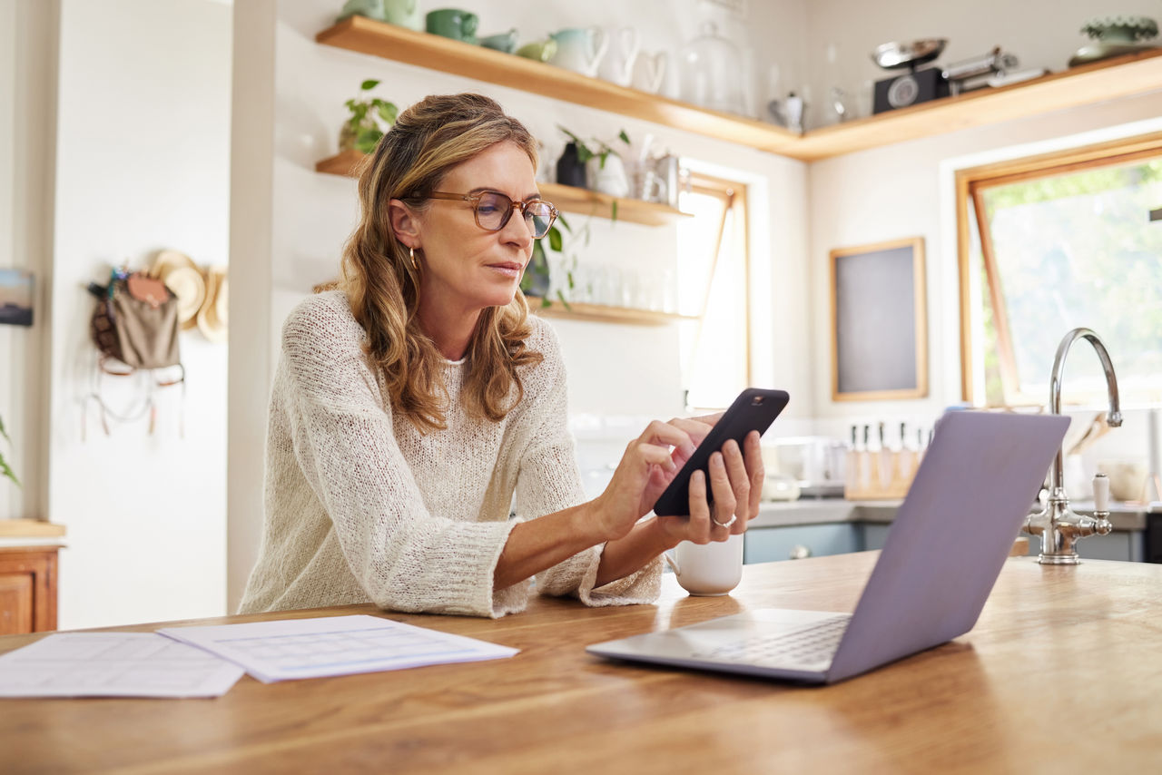 A woman using her smartphone in a kitchen
