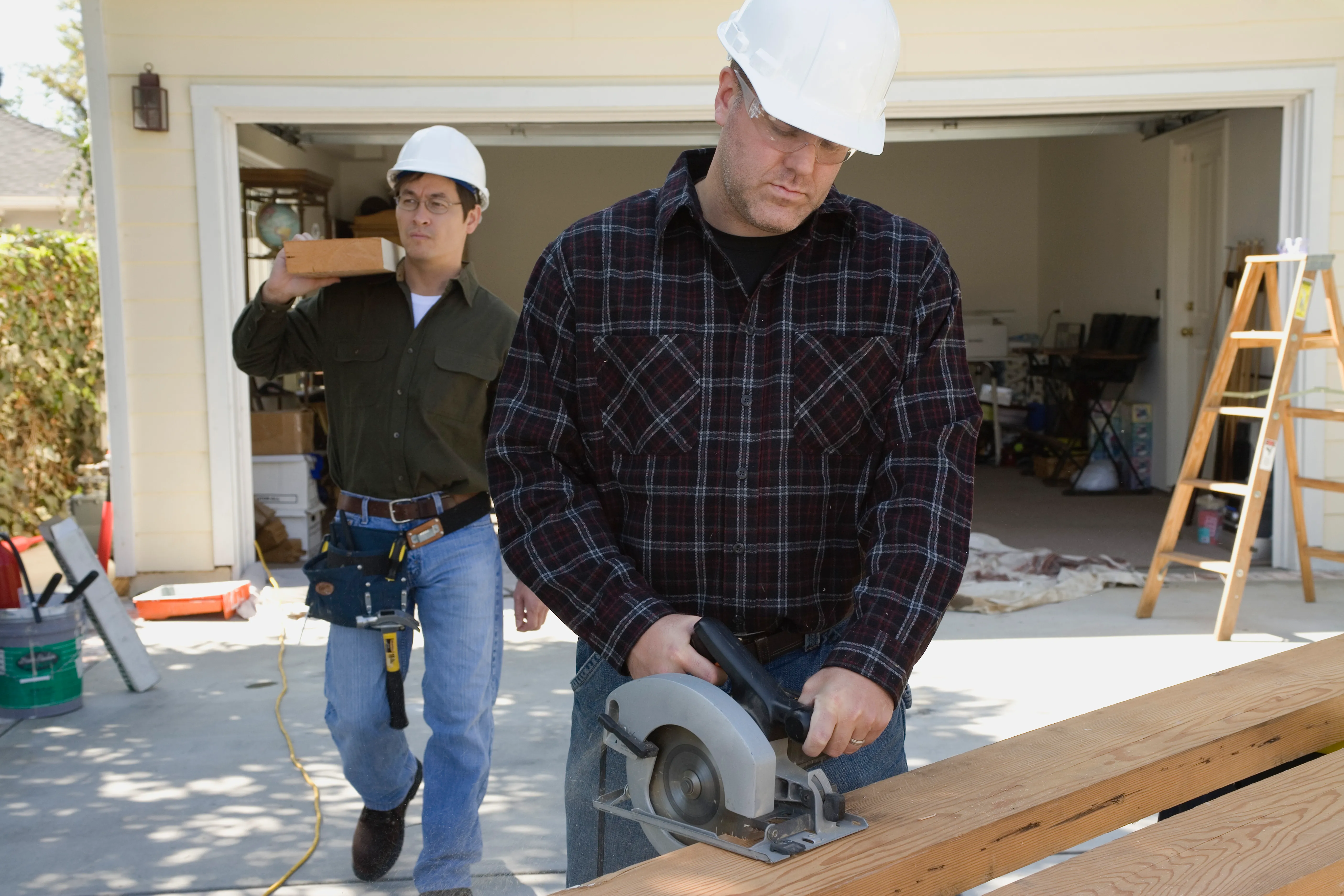 Two technicians working on garage door inspection and repair.