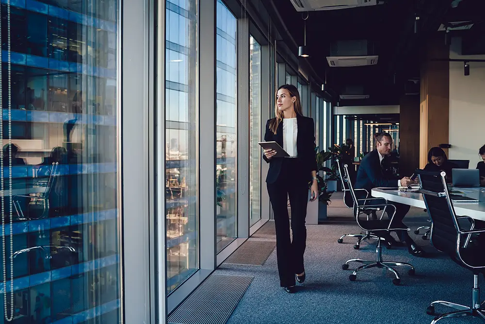 A woman walking into a meeting and looking out the window