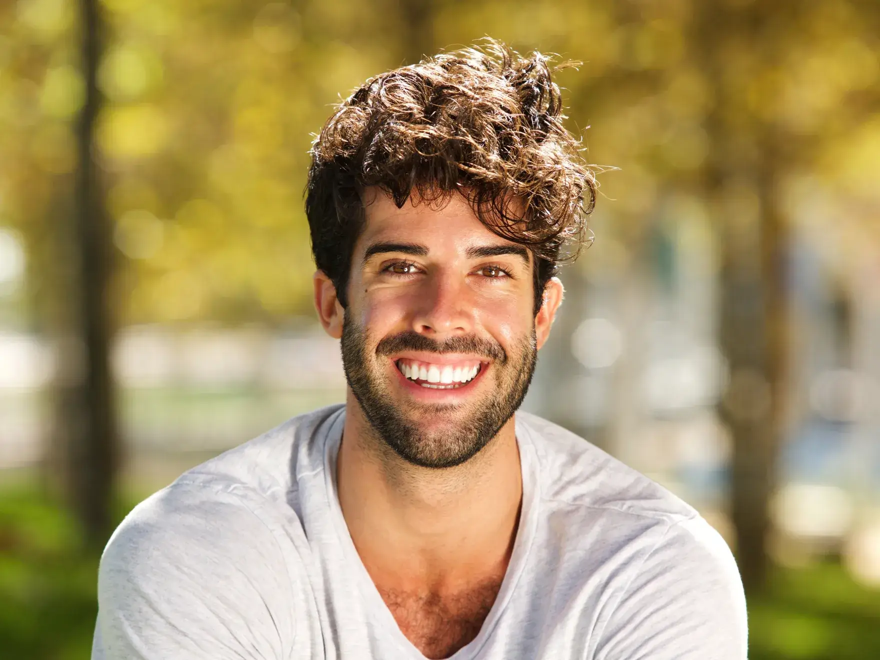 a man with curly hair smiling at the camera