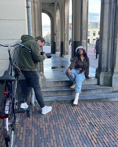 Robert Cornelisse fotografeert model Vonne tijdens een straatshoot bij een historisch gebouw, met een fiets op de voorgrond