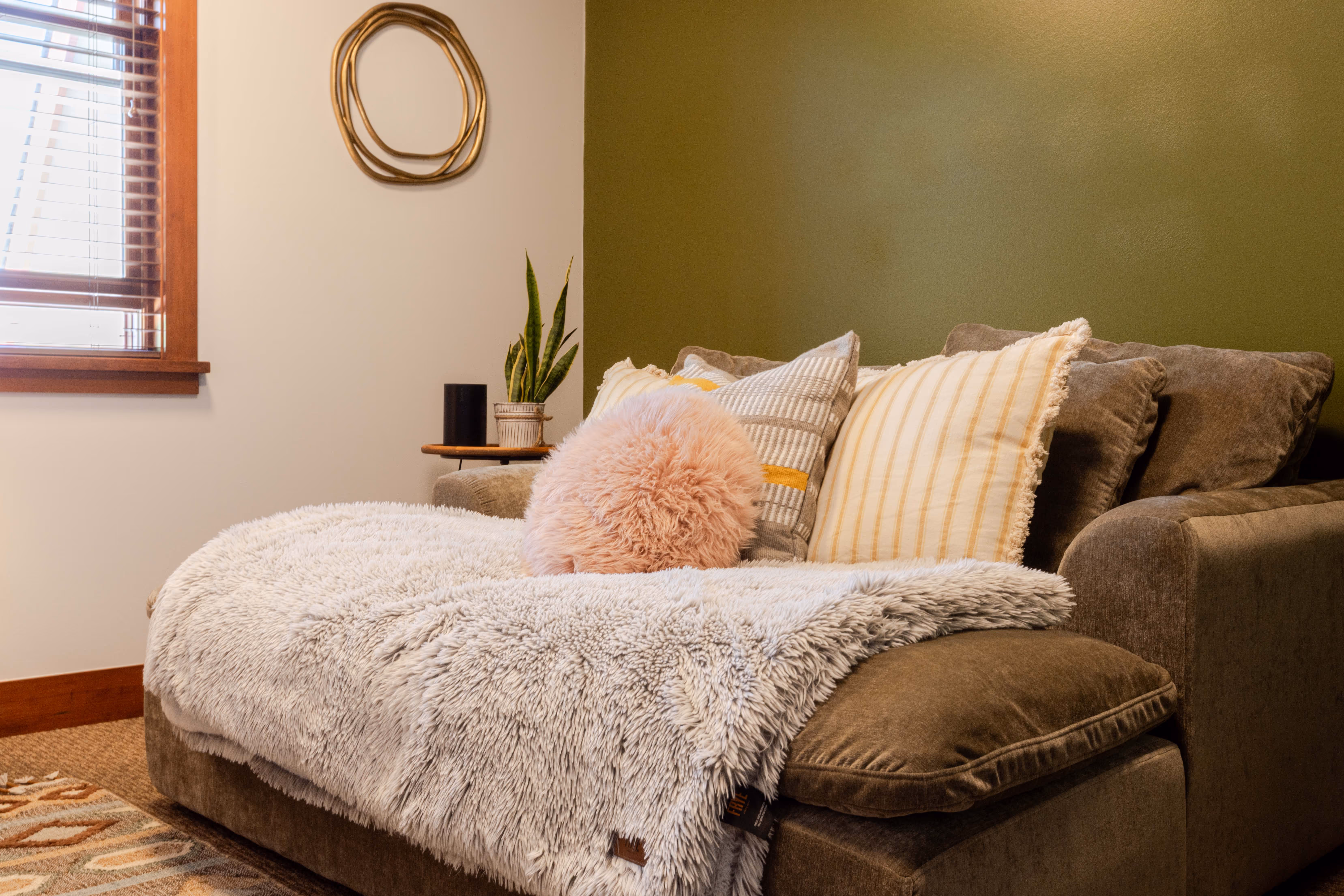 Cozy brown sofa with a soft gray throw and multiple decorative pillows in a living room.