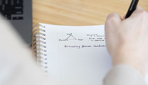 Someone drawing a simple triangle diagram on a piece of paper