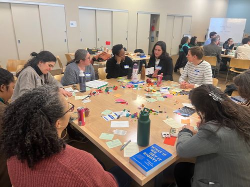 Group of people collaborating around a table with notes and materials during a facilitated workshop.