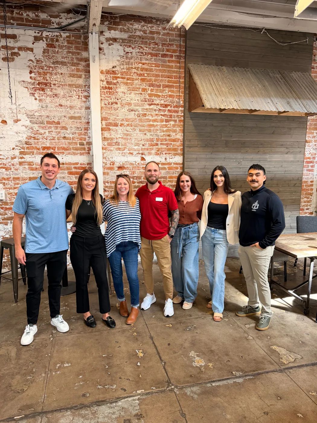 Shared Grounds sponsors standing together in front of a brick wall at The Porch in Prescott, Arizona