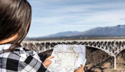 Woman holding a map with Rio Grande Gorge in background