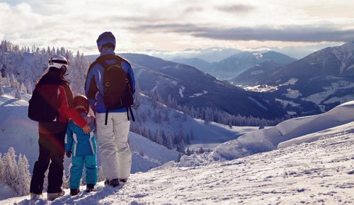 People dressed in winter gear standing in the mountains with snow