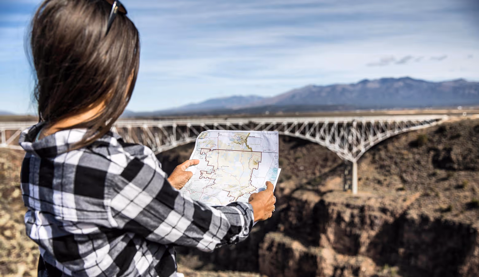 Woman holding a map facing the Rio Grande Gorge bridge