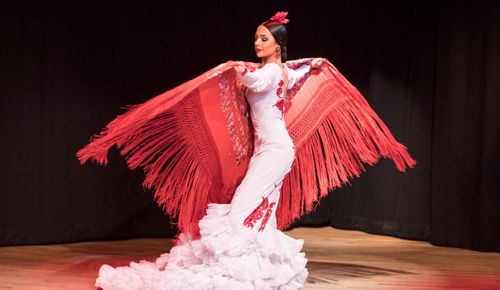 La Emi flamenco dancer on stage with white dress and red shawl