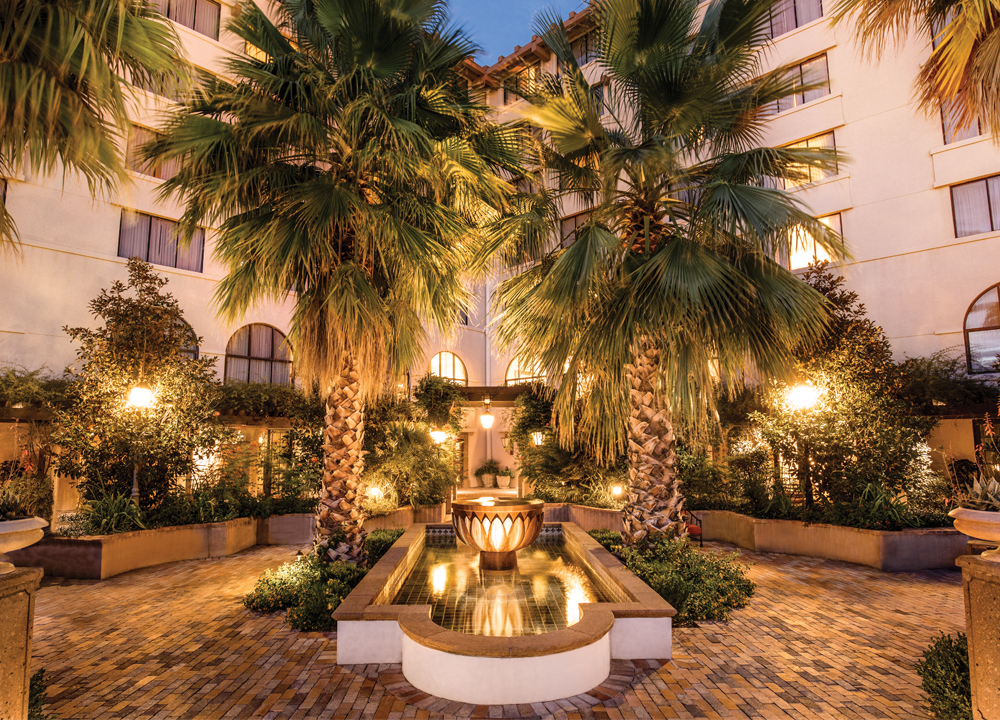 Hotel Encanto exterior at night with fountain and palm trees
