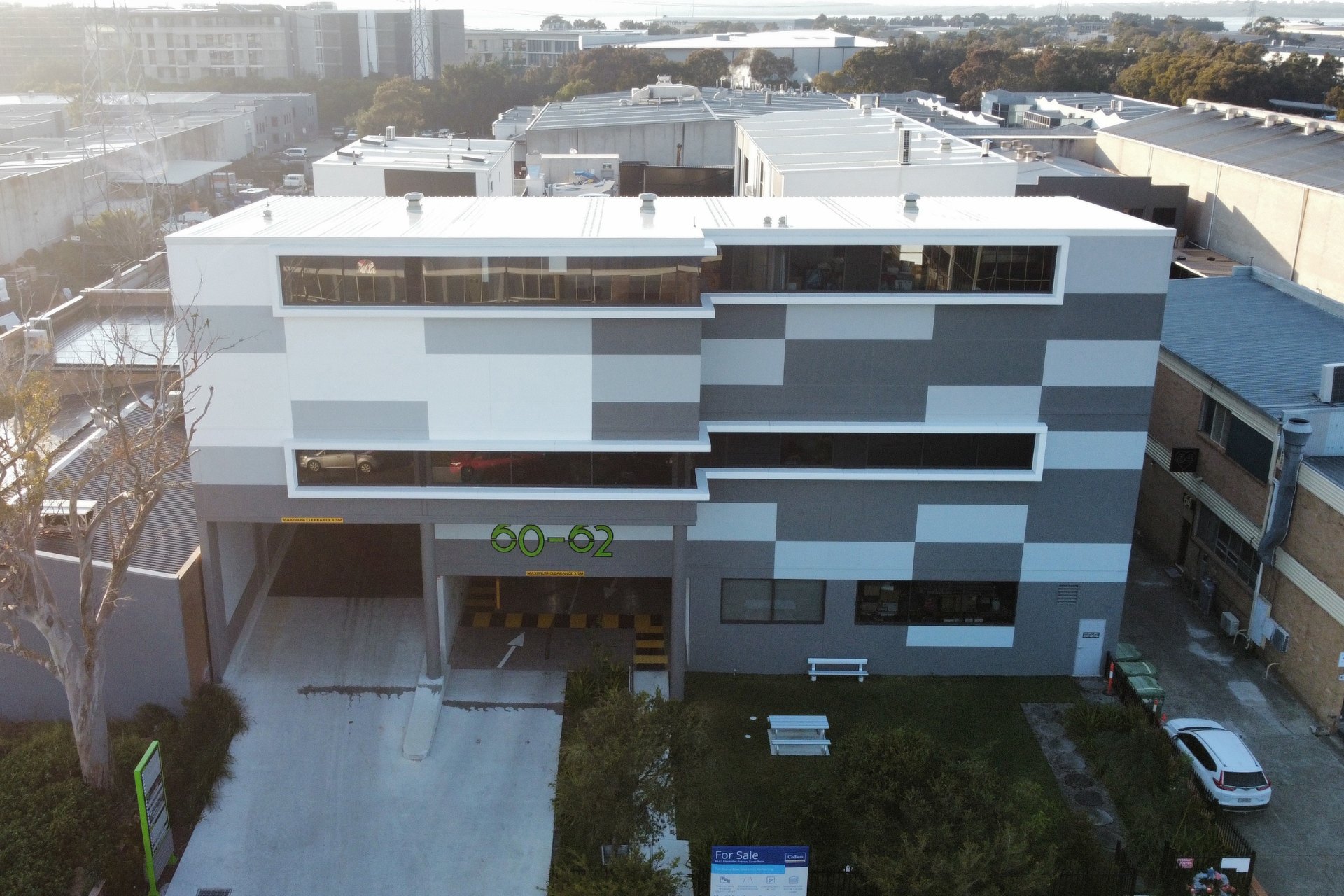 Modern commercial building with a geometric facade and clean commercial and industrial metal roofing. The structure sits in an urban setting with surrounding warehouses and roads.