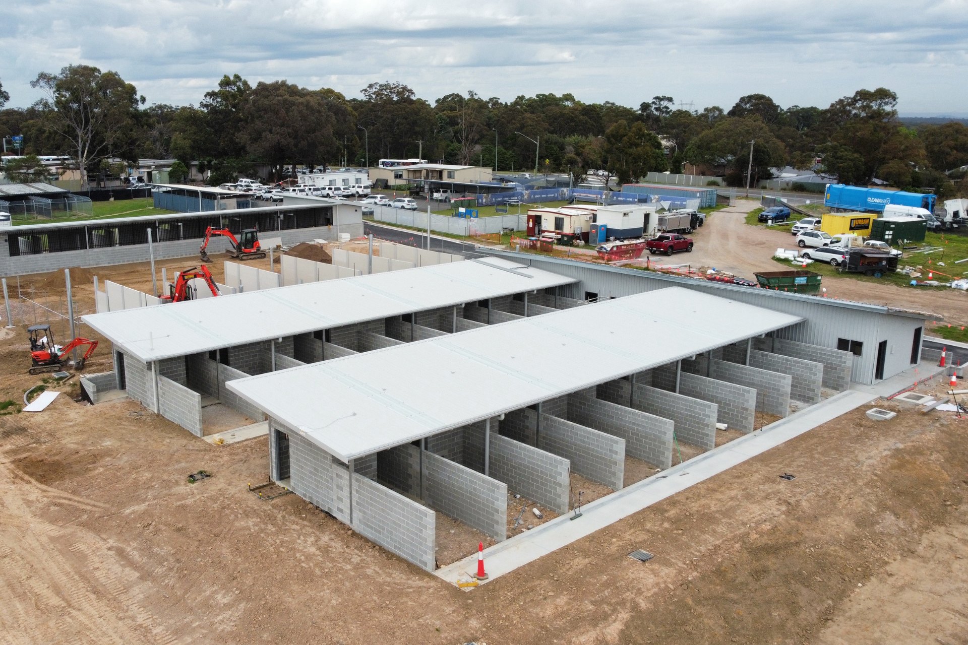 Construction site featuring a block of open stalls with clean, light-colored industrial roofing.