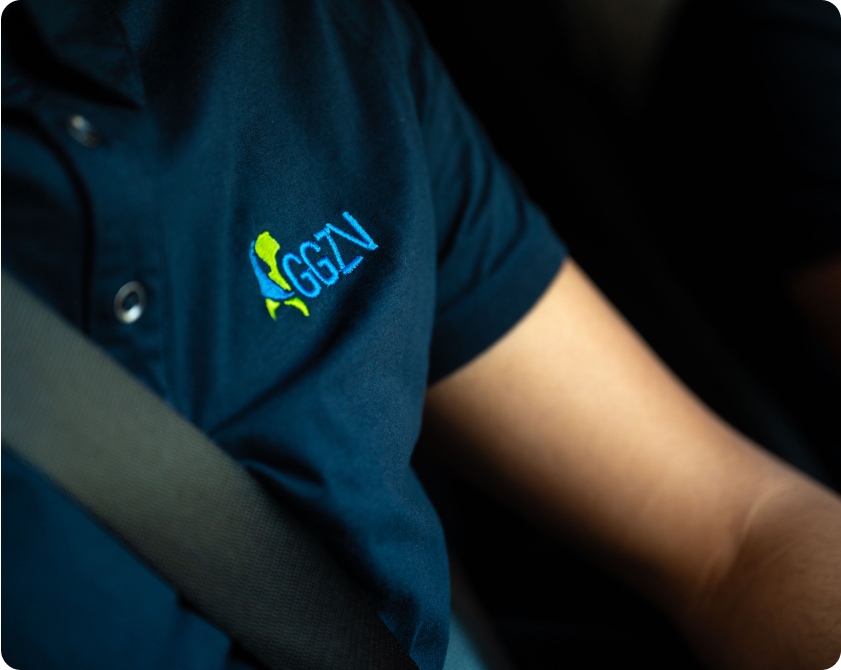 Begeleider van GGZ Vervoersdienst in polo met logo, met gordel om