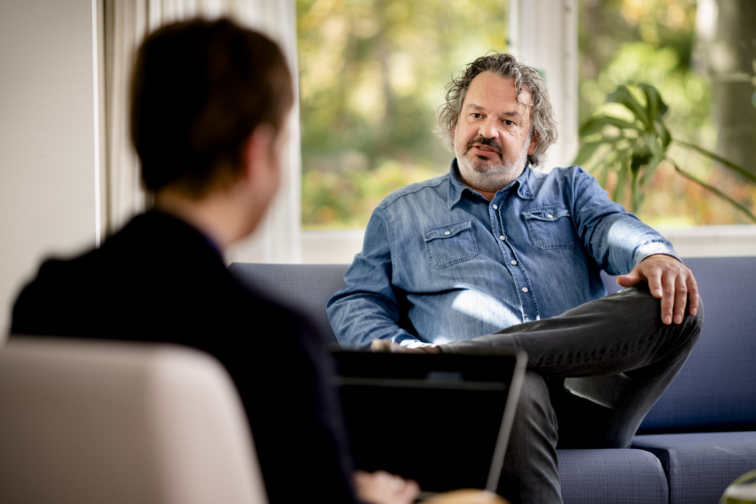 Gesprek tussen een hulpverlener en een man in een woonkamer