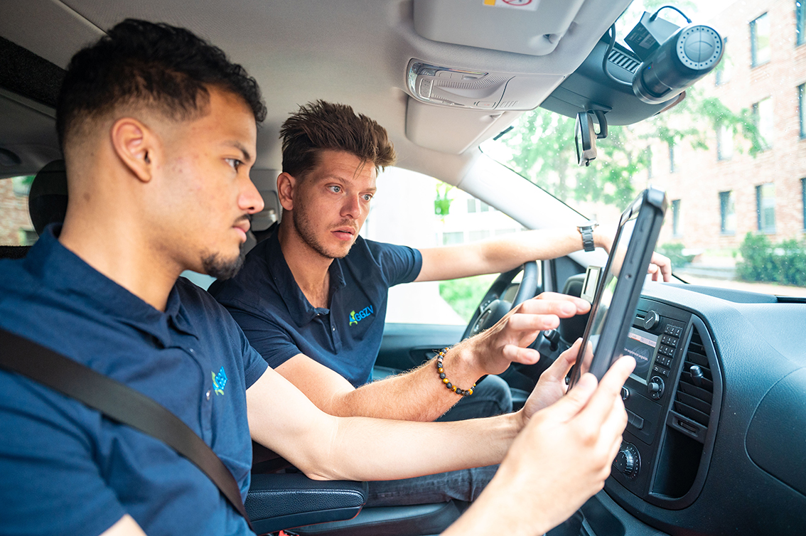 Twee medewerkers van GGZ Vervoersdienst in een auto met een tablet