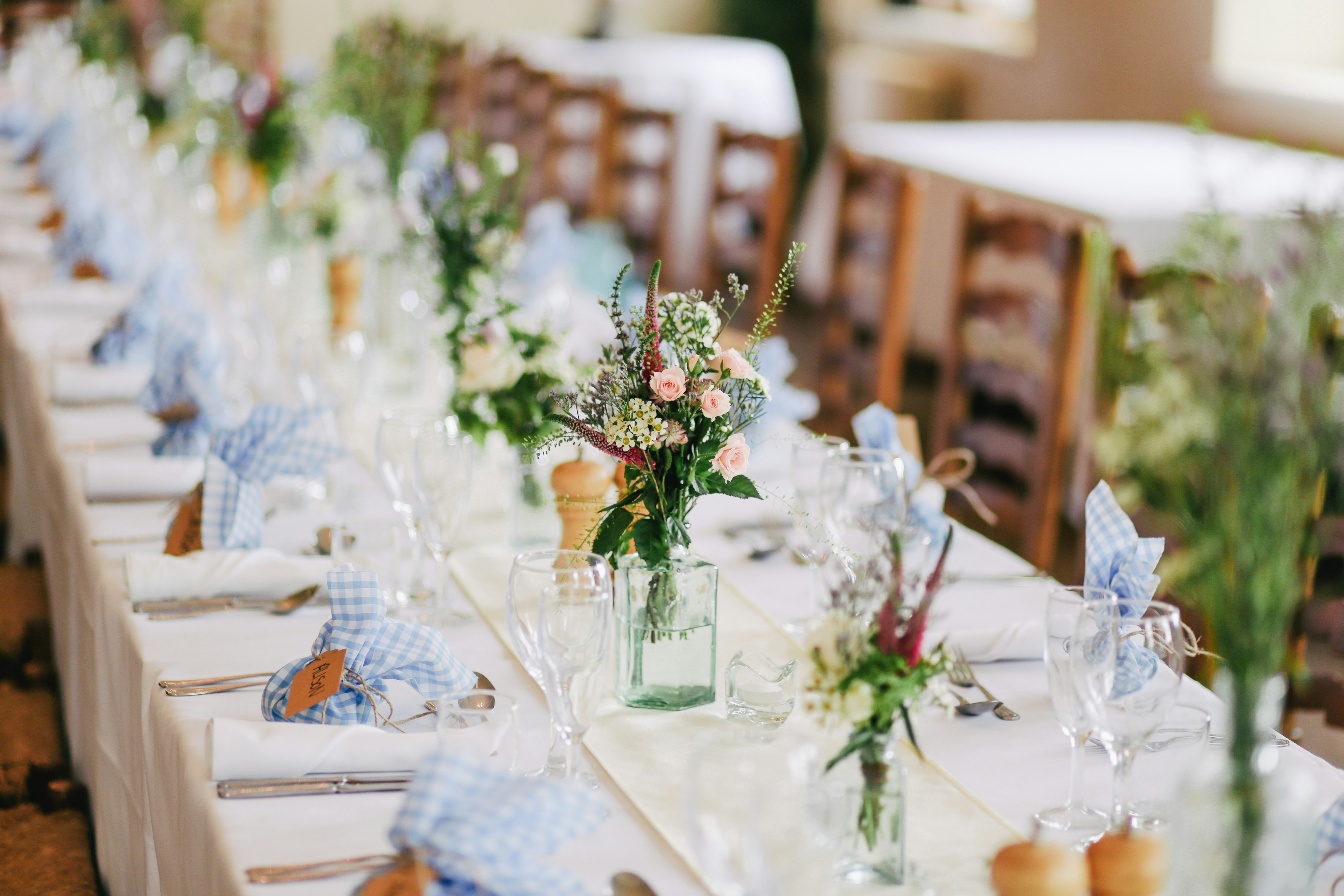 Image of wedding decoration on a white tablecloth with chairs in the background.