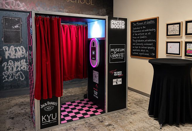 Photo booth with red curtains and pink checkered floor at Museum of Graffiti exhibit in Miami
