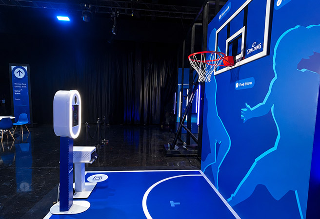Indoor basketball hoop setup in Miami on a blue court section with a digital photo booth nearby.