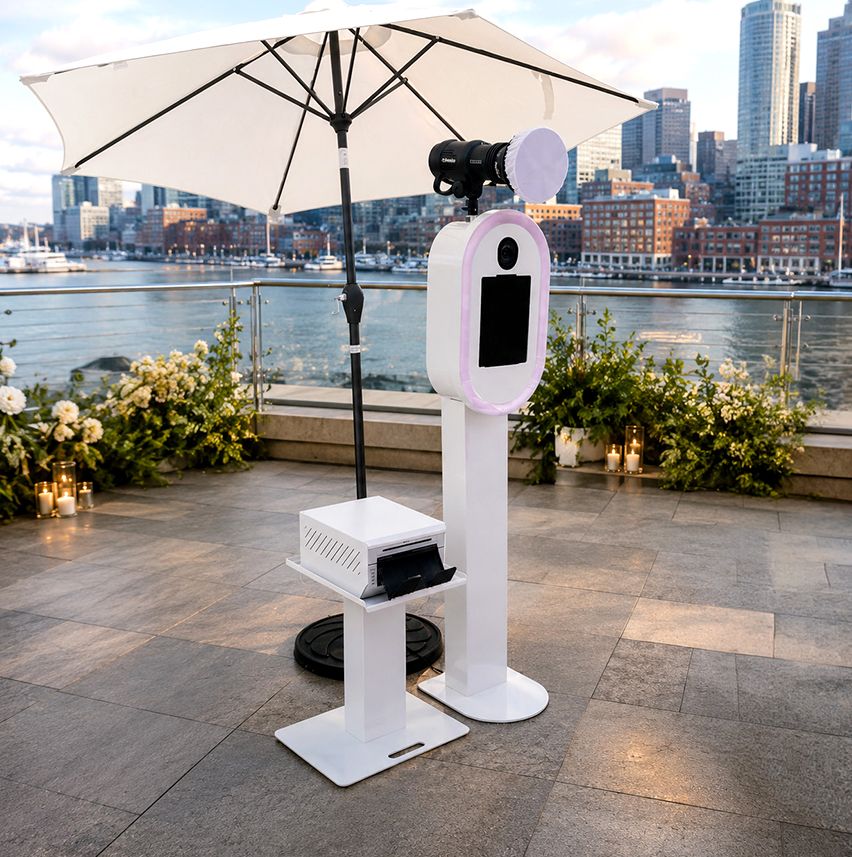 Capture Pod photo booth set up on an outdoor terrace overlooking Boston Harbor at dusk