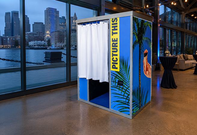 Blue custom-wrapped Capture Pod photo booth at a Boston waterfront venue overlooking the harbor