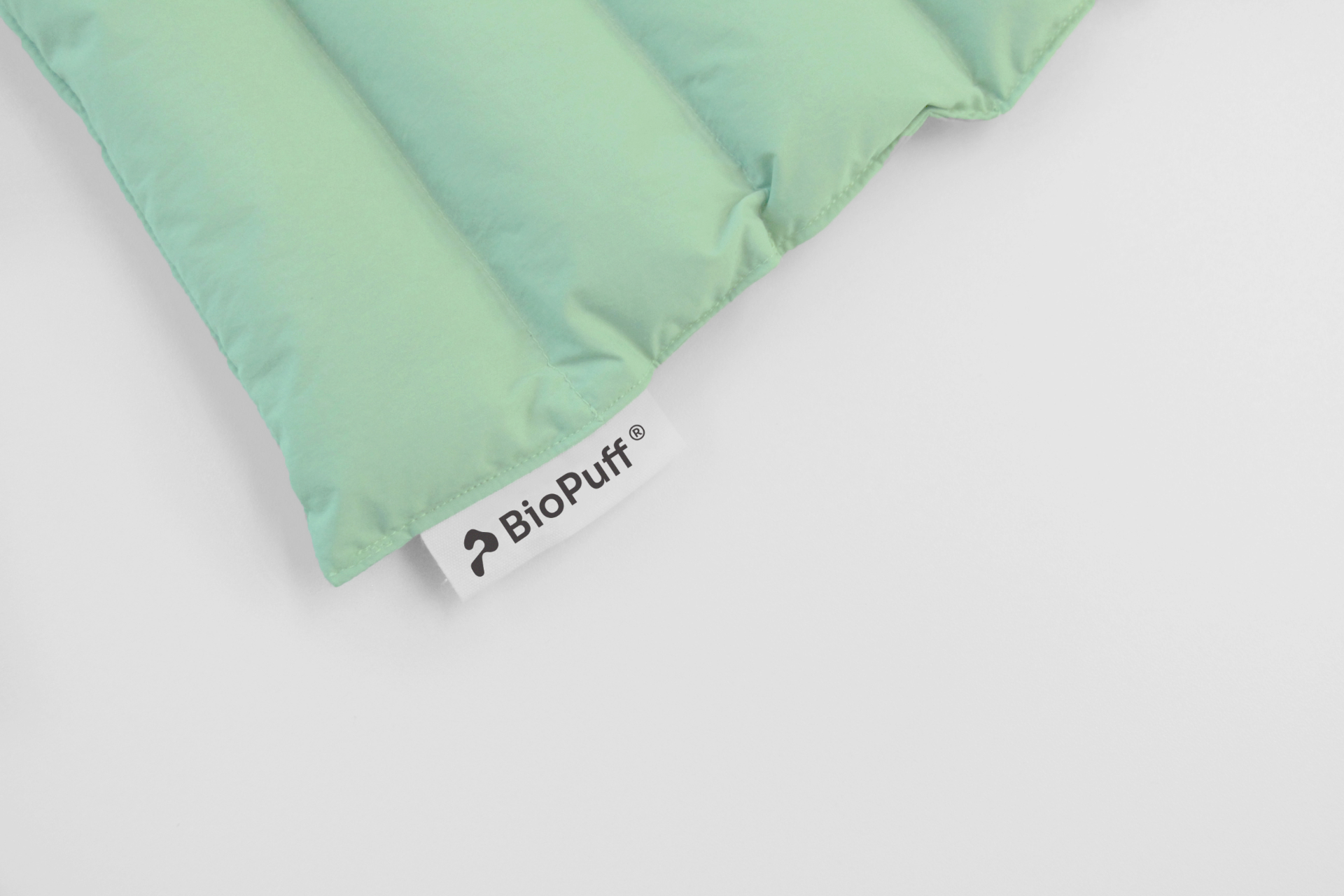 Close-up of a light green quilted fabric corner with a white tag labeled 'BioPuff'.