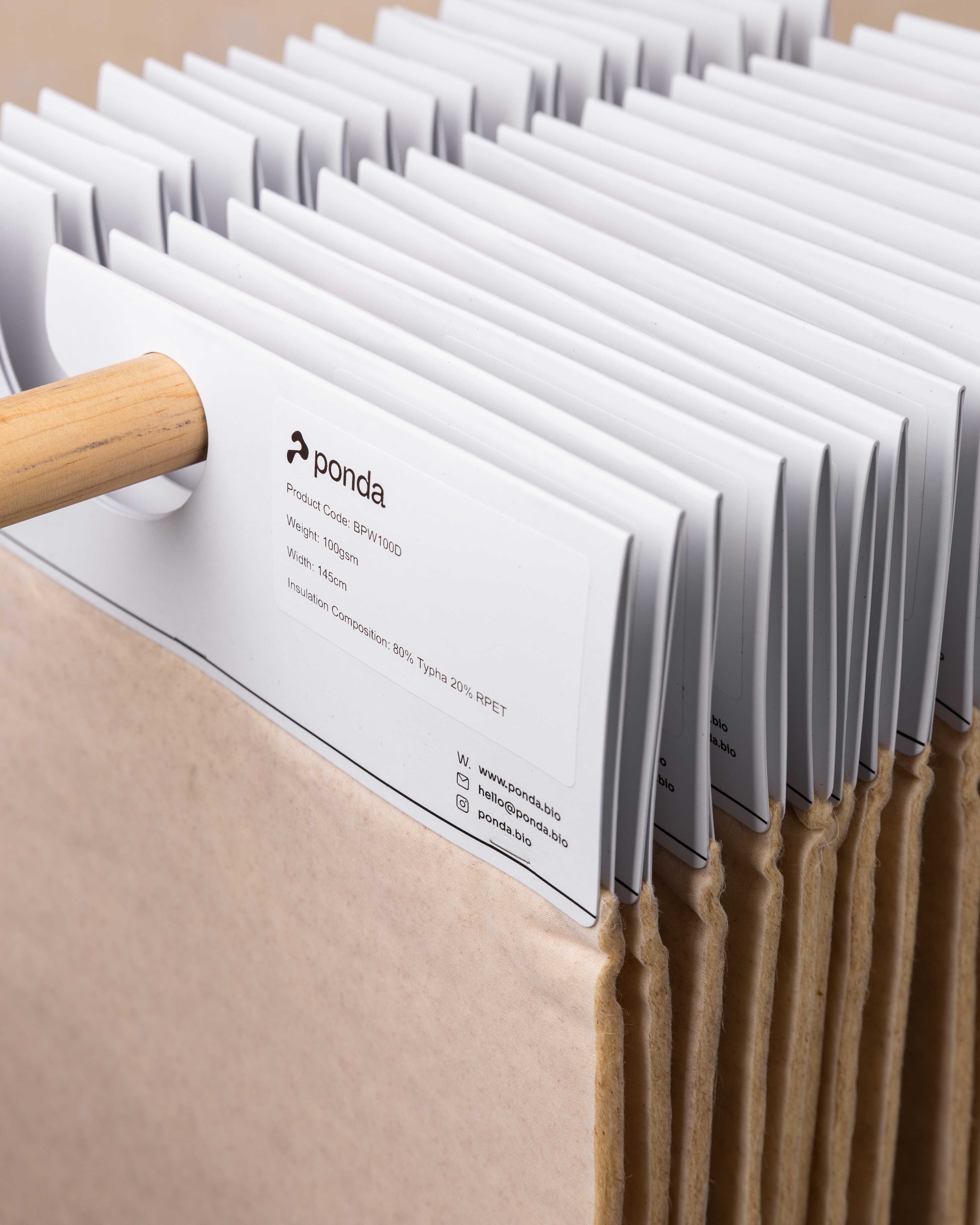 Stack of beige insulation material samples hanging on a wooden rod, labeled with product details from Ponda.