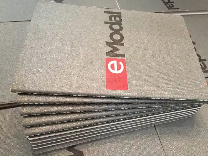 Premium grey textured stitched notebooks with printed Advent eModal logo for logistics software company branding.