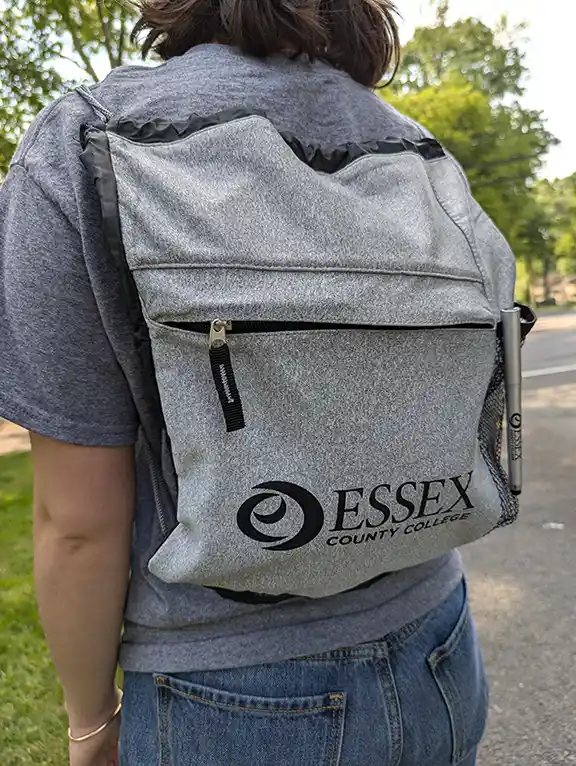 Custom imprinted drawstring bag featuring Essex County College logo in professional black ink. Premium grey heather construction with zippered pocket 
